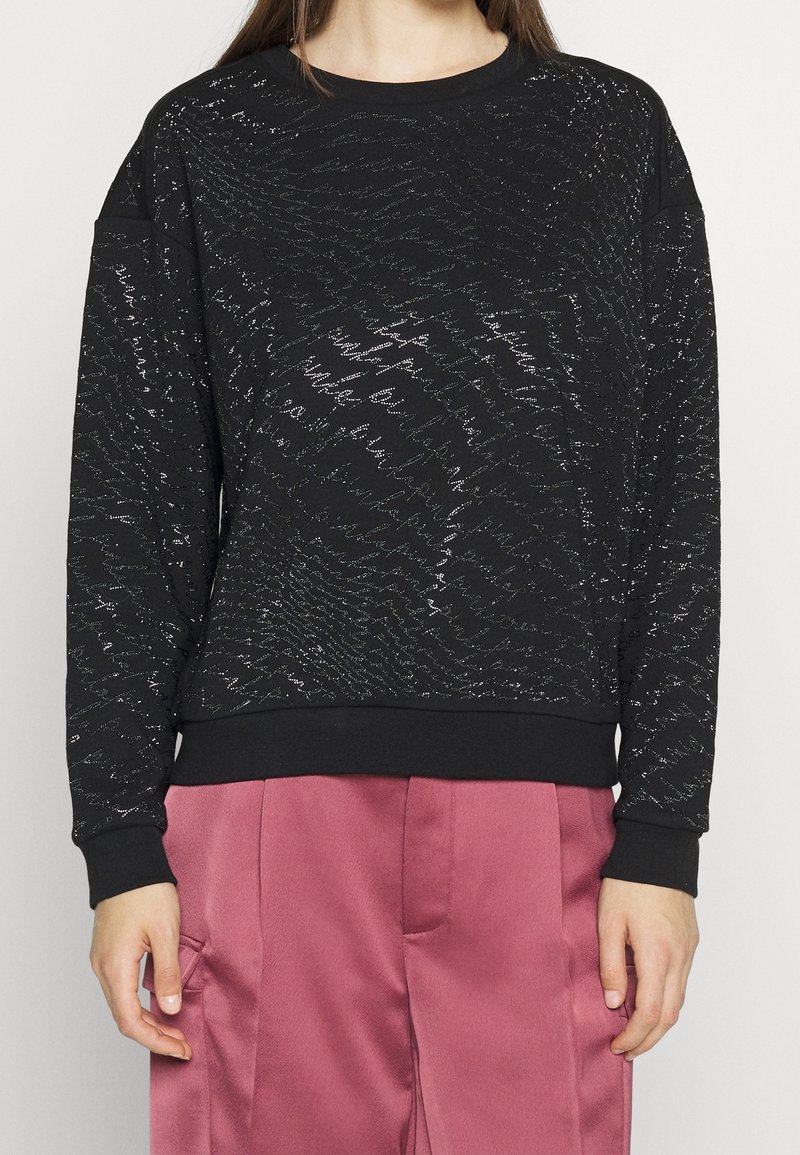 Sudadera negra con un patrón texturizado en zigzag, hecha de una tela suave. Presenta un escote redondo y puños y bajo acanalados.