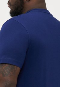 Camiseta de manga corta de color azul marino, confeccionada en una tela suave, con un cuello de tripulación clásico y detalles de costura sutiles en los hombros.
