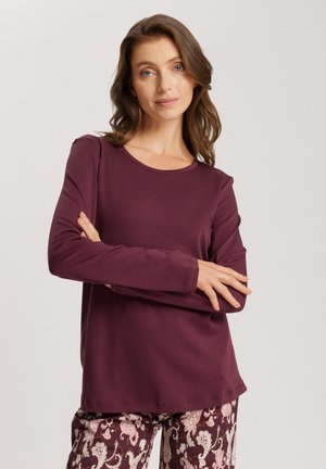 Chemise mauve à manches longues avec un col rond, fabriquée à partir d'un tissu doux. Associée à un pantalon à motifs avec un design cachemire.