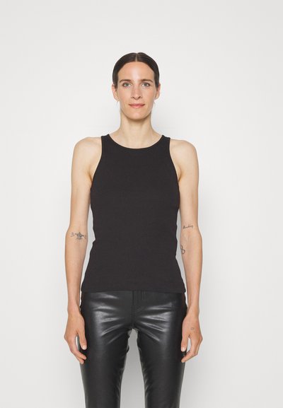 Black ribbed tank top with a round neckline, fitted design, and sleeveless cut. Paired with black fitted leather pants.