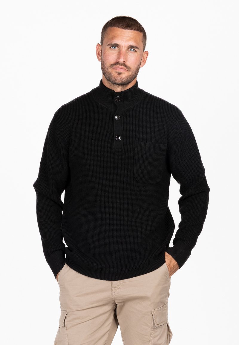 Pullover nero a maglia con colletto alto, tre bottoni e tasca sul petto. Presenta polsini e orlo a coste, creando un look texture.