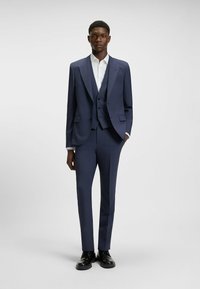 Completo tre pezzi blu navy composto da giacca, gilet e pantaloni tagliati su misura. Design strutturato con linee pulite e silhouette aderente.
