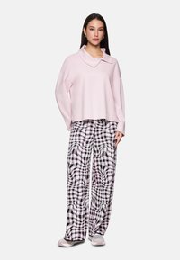 Light pink, oversized pullover with a wide collar paired with black and white plaid wide-leg pants featuring swirling patterns and soft texture.
