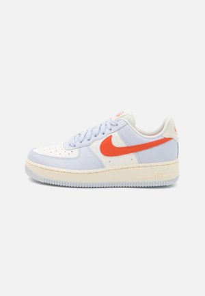 Baskets Nike Air Force 1 en cuir bleu clair et blanc, avec un swoosh orange, une surface texturée et une semelle couleur crème.