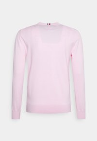 Jasnoróżowy sweter z długim rękawem, wykonany z miękkiego materiału dzianinowego, z okrągłym dekoltem i ściągaczami na mankietach. Posiada małe logo na karku.