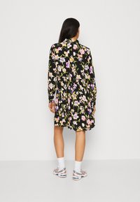 Vestito floreale con maniche lunghe, sfondo nero, fiori multicolori, forma ad A, lunghezza al ginocchio, chiusura posteriore con bottoni, tessuto leggero.