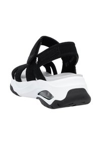 Sandale en tissu noir avec des sangles entrecroisées, semelle intermédiaire blanche et semelle extérieure noire. Caractéristiques : sangles réglables pour un maintien sécurisé et détails en matière de rembourrage.