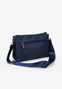 Bolso bandolera de cuero azul marino con acabado texturizado, compartimento principal con cremallera y correa de satén ajustable. Cuenta con un bolsillo frontal con cremallera.