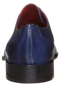 Scarpe in pelle blu navy con una texture liscia e forma arrotondata. Fodera interna rossa e suola piatta nera. Dettaglio della cucitura posteriore visibile.