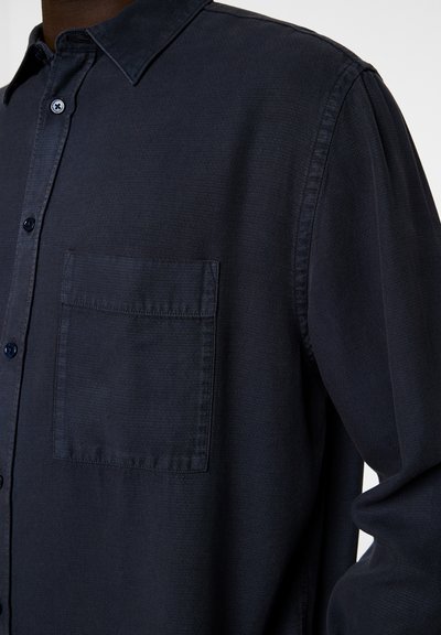 Navy button-up shirt with a collar, textured fabric, single chest pocket, and dark buttons. Focus on solid color and structured design.