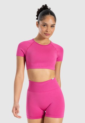Heldere roze sportoutfit bestaande uit een cropped top met korte mouwen en high-waisted shorts, gemaakt van soepele, rekbare stof.