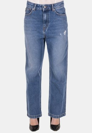 Jeans blu a gamba dritta con leggero effetto vissurato, indossati con décolleté nere con punta affilata e top bianco infilato dentro.