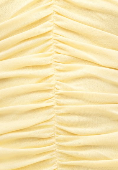 Tissu jaune doux avec fronces verticales créant des plis rassemblés uniformément espacés le long de la couture centrale.