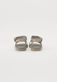Gray sandals made of fabric with a textured footbed, featuring two back straps for support and a flat rubber sole.
