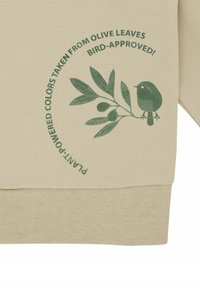 Beige Sweatshirt mit grünem Blatt- und Vogel-Graphic. Enthält Text: "Pflanzenkraft-Farben inspiriert von Olivenblättern. Vogel-geprüft!"