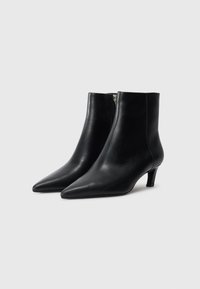Black leather ankle boots with pointed toes, side zippers, and low kitten heels, shown against a plain white background.