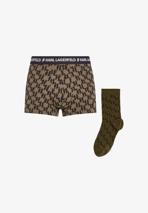 smeđi bokserice s crnim apstraktnim uzorcima i crnim pojasom. Maslinasto zelene čarape imaju tamni uzorak. Oba predmeta su izrađena od mekanog materijala.