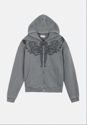 Szürke cipzáras kapucnis pulóver elülső zsebekkel és fekete szárnyas kereszt grafikával a mellkason és a vállakon, kapucnival és bordázott mandzsettákkal.