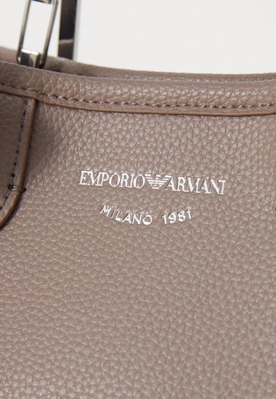 Brown textured leather bag featuring a silver "Emporio Armani Milano 1981" logo embossed on the front. Minimalistic design with sleek hardware.