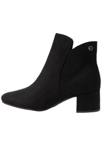 Černé nubukové kotníkové boty s nízkým blokovým podpatkem, špičatou špičkou a malým kulatým kovovým logem blízko horní zadní části.