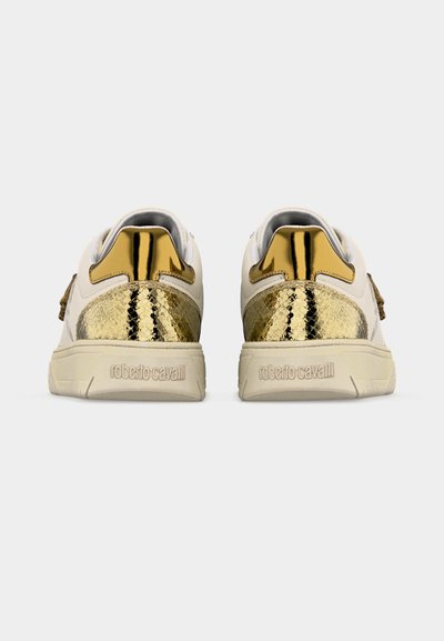 Baskets basses blanches et dorées avec des panneaux de talon texturés en or et des accents dorés brillants, nom de la marque embossé sur des semelles beiges.