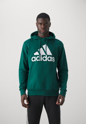 Felpa verde in cotone con un grande logo Adidas bianco. Presenta cordini, una tasca a marsupio frontale e polsini a coste sulle maniche.
