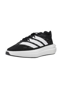 Baskets de sport noires avec un design à trois rayures blanches, tige texturée, embout arrondi et une épaisse semelle intermédiaire blanche. Équipées d'un système de laçage.