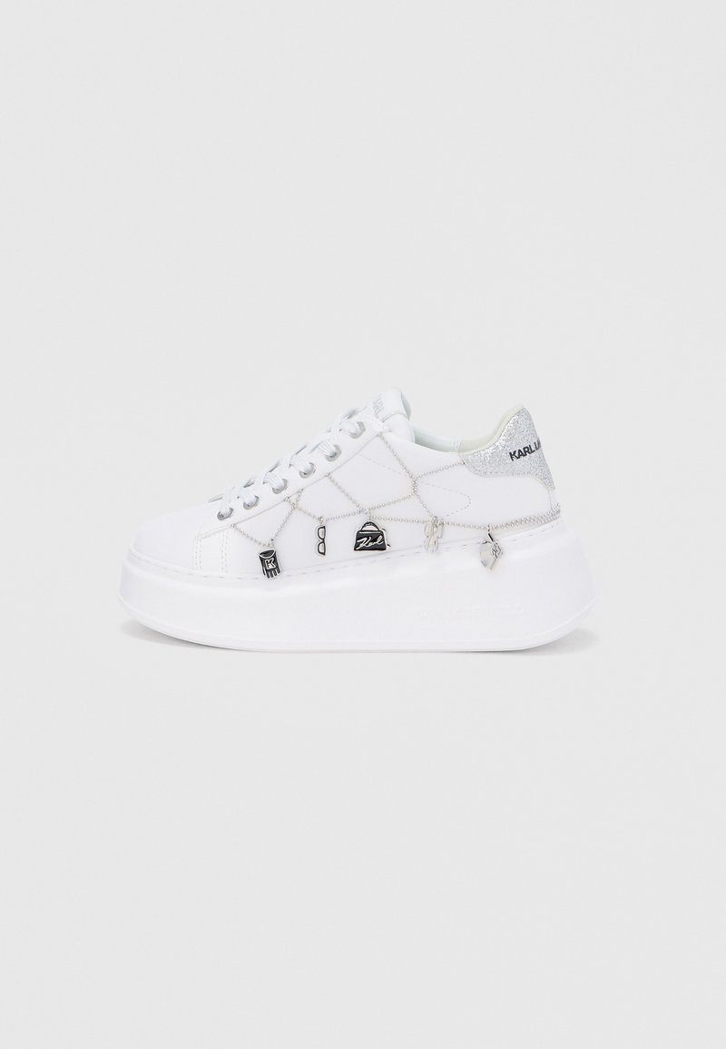 Adidași platformă albi cu suprafață texturată, cu accente argintii, talismane decorative și detalii cusute pe părți.