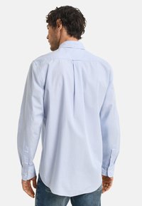 Helles blaues Hemd mit langen Ärmeln, das eine Rückenfalte, einen Button-Down-Kragen und geknöpfte Manschetten aufweist, hergestellt aus einem glatten Stoff.