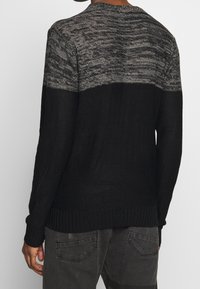 Czarny i szary dziergany sweter z pulowerem, z fakturowaną górną częścią, ściągaczem u dołu i długimi rękawami.