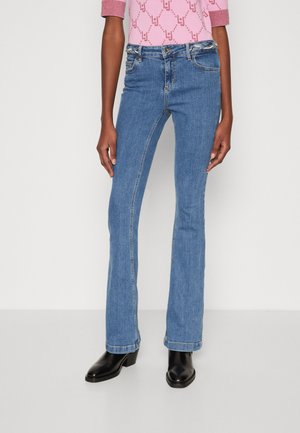 Jeans in denim azzurro chiaro a zampa d'elefante, a vita media, con tasche anteriori e leggere sfumature. Indossati con stivaletti neri con tacco.