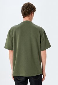 Mintgrøn kortærmet T-shirt med rund hals, lavet af tekstureret bomuld, med en afslappet pasform og lige kant.