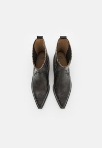 Schwarze Leder Stiefeletten mit spitzen Zehen, dekorativen Nähten und strukturierten Akzenten. Sie verfügen über einen niedrigen Absatz und elastische Seitenpaneele.