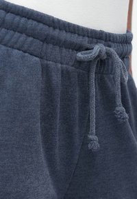 Dark blue sweatpants made of soft fabric, featuring an elastic waistband with a drawstring and textured accents on the sides.