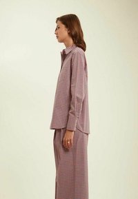 Ensemble chemise et pantalon à carreaux dans des couleurs rose, bleu et blanc. Tissu léger, poignets à bouton, et design décontracté.