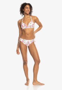 Bikini-set met bloemenpatroon in een roze en witte kleurenschema. Driehoekig topje met verstelbare bandjes en bijpassende bikini-broekjes met striksluiting aan de zijkant.