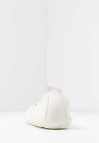 Vita läderballettskor med rund tå, utrustade med en bakflik och en slät yta. Minimalistisk design, utan synliga dekorationer.