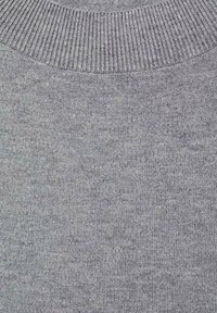 Gros plan sur un tissu tricoté gris avec un col crew à côtes, montrant une texture de tricot fine et des détails de coutures.