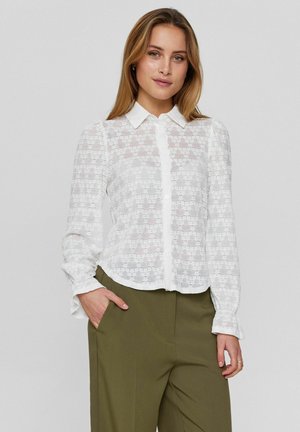 Witte semi-doorzichtige blouse met een patroon van kantstructuur, lange mouwen, kraag en een asymmetrische zoom, gecombineerd met olijfgroene broek.