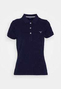 Mörkblå polo skjorta med klassisk krage, korta ärmar, tre-knapps knäppning och liten logotyp på vänster bröst. Material av bomull.