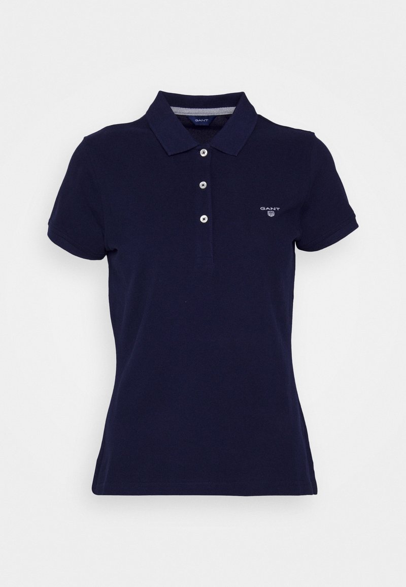 Mörkblå polo skjorta med klassisk krage, korta ärmar, tre-knapps knäppning och liten logotyp på vänster bröst. Material av bomull.