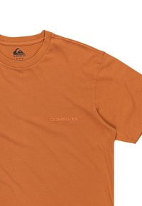 Orange cotton t-shirt with a crew neckline, short sleeves, and a subtle embossed "Quiksilver" logo on the front. Smooth texture.