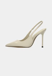 Escarpins beige en cuir verni à bride arrière, avec un bout pointu, un talon haut stilettos et un design ouvert à l'arrière. Surface lisse avec peu de détails.