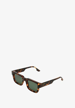 Gafas de sol de carey con montura cuadrada, lentes verdes y sutil branding en las patillas. Material de plástico suave y diseño angular.