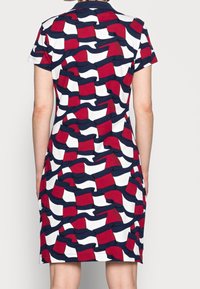 Kurzärmliges Kleid mit einem wellenförmigen Muster in Rot, Marineblau und Weiß. Hergestellt aus einem glatten Stoff mit einem klassischen Polokragen.