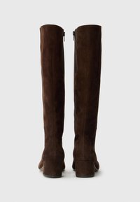 Knee-high brown suede boots with a smooth texture, block heels, and side zippers for easy wear. Simple and sleek design.