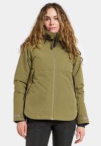 Veste isolante verte olive avec un col montant, fermeture éclair, capuche ajustable et poignets contrastés. Texture lisse, design pratique.