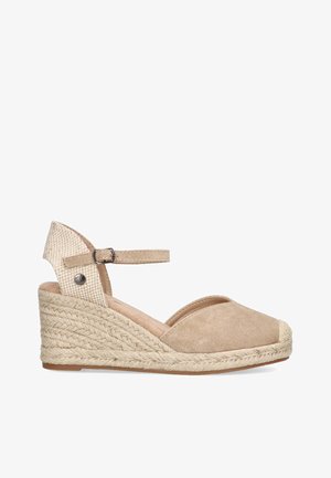 Sandalia de cuña beige de espadrille con tirante de tobillo, parte superior de ante y suela trenzada de yute. Punta redondeada y detalle texturizado en la parte posterior.