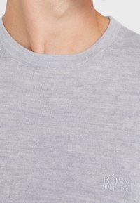 Sweat léger gris avec une texture côtelée, un col rond, et un logo BOSS en relief dans le coin inférieur droit.