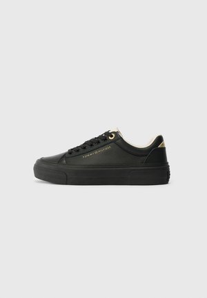 Black leather sneaker with a smooth texture, featuring gold accents and a round toe. Thick black rubber sole and tonal laces.